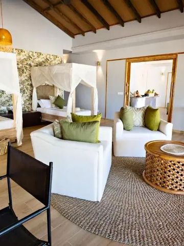 Wohnbereich mit gemütlichen Sesseln und Himmelbetten im Hintergrund