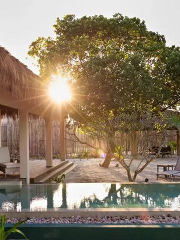 Sonnenuntergang am Pool mit strohbedecktem Pavillon und üppiger Vegetation