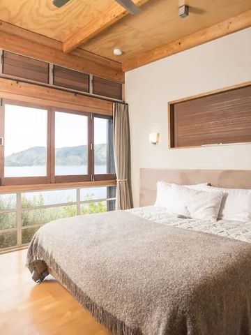 Gemütliches Schlafzimmer mit Holzdecke und großem Bett mit Seeblick