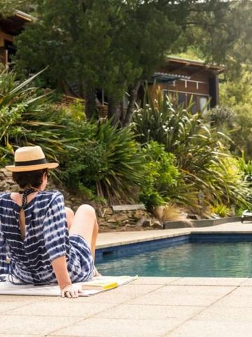 Frau entspannt sich am Pool mit Blick auf die umliegende Natur