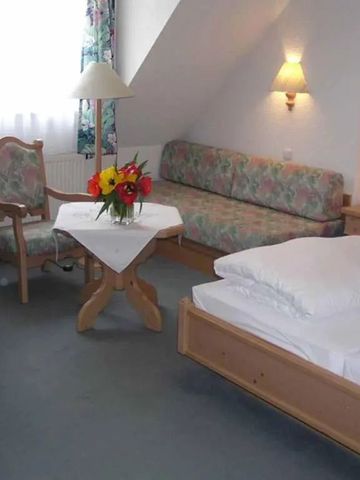 Komfortables Hotelzimmer mit Doppelbett und Blumenarrangement in heller Einrichtung.