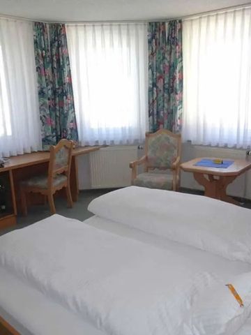 Helles Eckzimmer mit Doppelbett, Fernseher und geschmackvoller Holzausstattung.