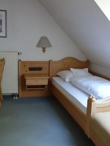 Einzelzimmer unter dem Dach mit Holzmöbeln und gemütlichem Ambiente.