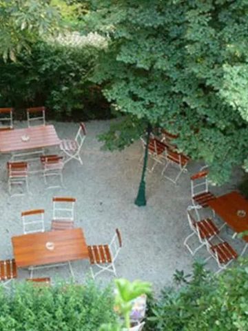 Gemütlicher Gartenbereich mit Holztischen und Stühlen unter Bäumen