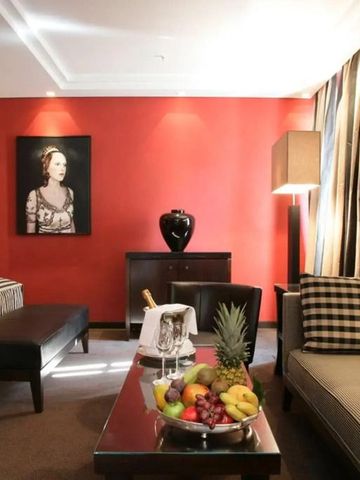 Luxuriöses Hotelzimmer mit roter Akzentwand und gemütlicher Sitzecke.