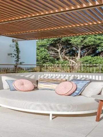 Sonnige Terrasse mit komfortabler Sitzlounge und Holzdach