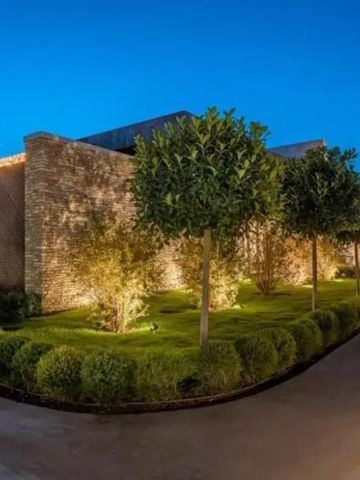 Beleuchtete Gartenfassade in der Abenddämmerung mit gepflegter Vegetation
