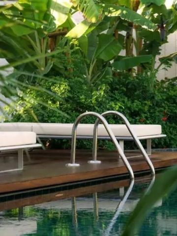 Luxuriöser Poolbereich umgeben von üppigem Grün und Liegestühlen