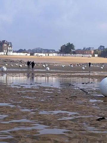 Weitläufiger Strand mit Blick auf das Meer und nahegelegene Gebäude