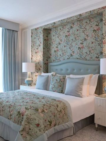 Luxuriös gestaltetes Schlafzimmer mit floralen Tapeten und weichen Farben