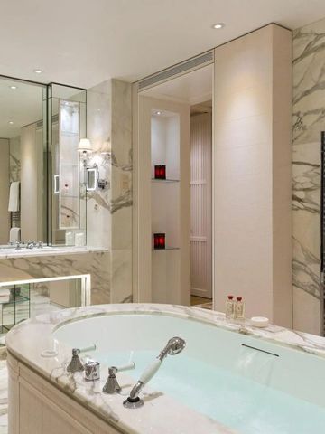 Luxuriöses Badezimmer mit Marmorwänden und freistehender Badewanne