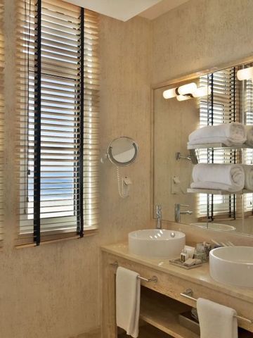 Elegantes Badezimmer mit zwei Waschbecken und Meerblick durch Jalousiefenster