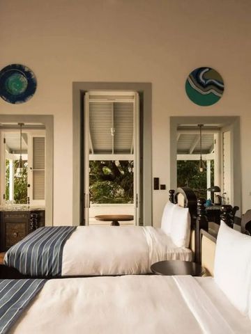 Zwei Einzelbetten in einem Zimmer mit dekorativen Wandteller und Gartenblick