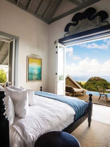 Schlafzimmer mit offenem Zugang zu Terrasse und Meerblick in der Ferne