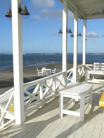 Strandterrasse mit weißem Holzmobiliar und Meerblick