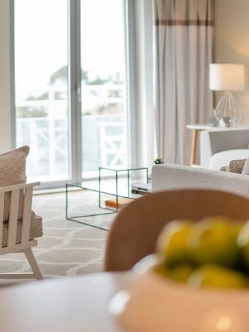 Helles Wohnzimmer mit modernen Möbeln und großem Fenster mit Meerblick