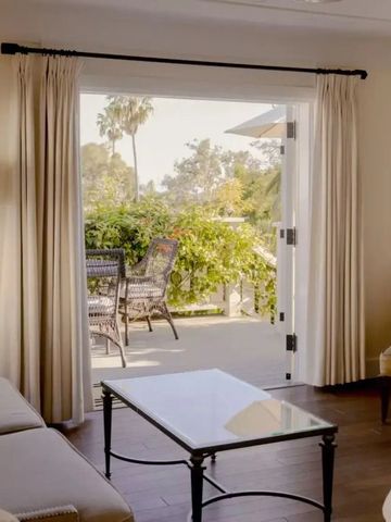 Helle Suite mit Balkonblick auf Garten und Palmen.