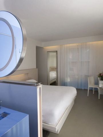 Helles Hotelzimmer mit großem Bett und blauer Trennwand