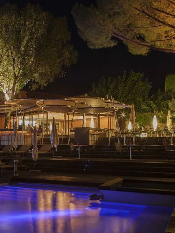 Abendliche Poollandschaft mit beleuchtetem Pool und Bäumen