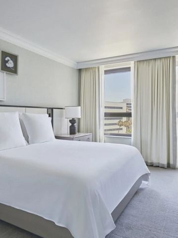 Helles Gästezimmer im Beverly Wilshire mit großem Bett und Ausblick auf die Stadt.