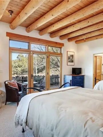 Helles Schlafzimmer mit Holzbalkendecke und Zugang zur Terrasse.