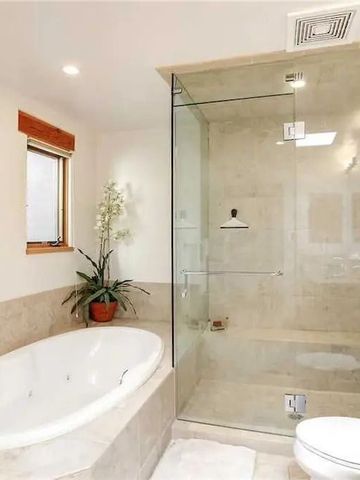 Luxuriöses Badezimmer mit freistehender Badewanne und verglaster Dusche.