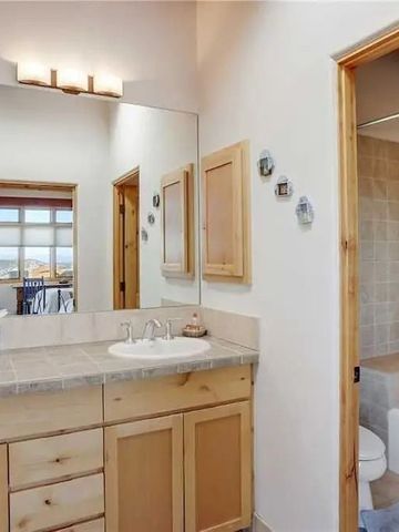 Badezimmer mit hellem Holzmobiliar und großer Spiegelwand.