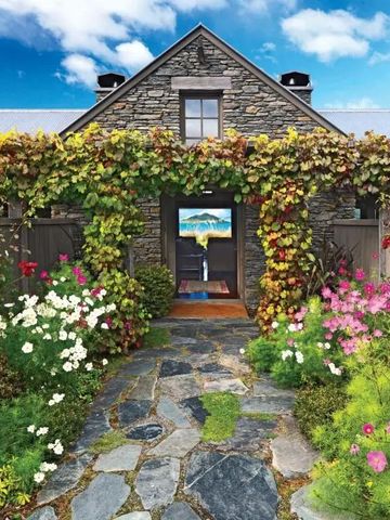 Historisches Steingebäude mit blühendem Garten und blauem Himmel