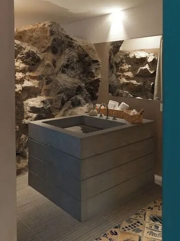 Elegantes Badezimmer mit Natursteinwand und Betonwaschbecken