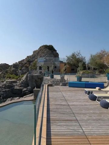 Terrasse mit Liegestühlen und Blick auf felsige Küste