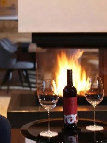 Weinflasche und Gläser vor einem Kamin in einer gemütlichen Lounge
