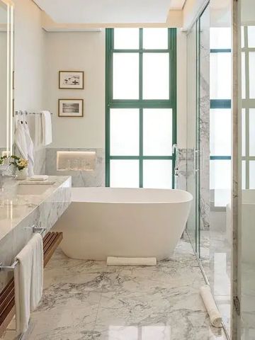 Stilvolles Badezimmer mit freistehender Badewanne und Marmoroberflächen.