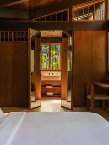 Schlafzimmer mit einem Bett, Holzinterieur und Blick in einen grünen Garten.