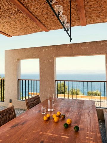 Terrasse mit Holztisch und Meerblick im Hintergrund