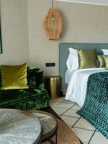 Elegantes Hotelzimmer mit grüner dekorativer Akzentwand und gemütlichem Bett