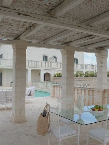 Terrasse mit eleganten weißen Möbeln und Blick auf einen Pool.