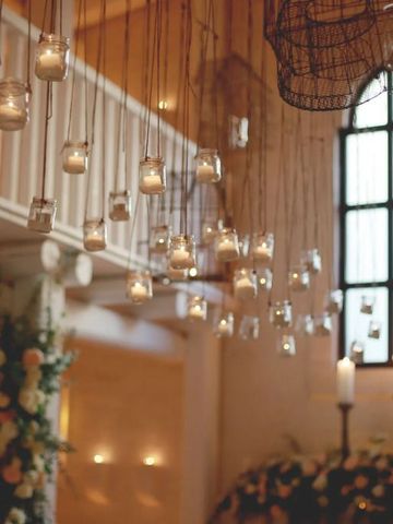 Stimmungsvoll dekorierter Raum mit hängenden Kerzen und großen Fenstern