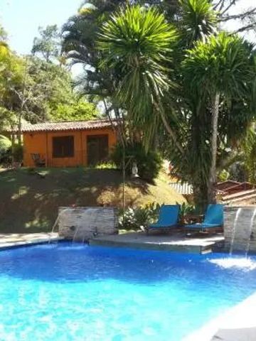 Pool mit Wasserfall und umgeben von üppiger Vegetation und Liegestühlen