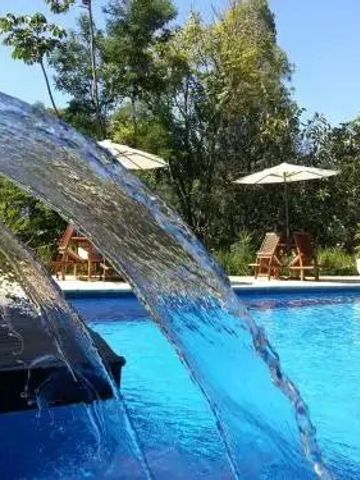 Nahaufnahme eines kaskadierenden Wasserfalls in einem blauen Pool mit umliegenden Liegestühlen