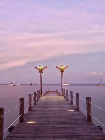 Steg am Meer bei Sonnenuntergang mit Segelbooten am Horizont