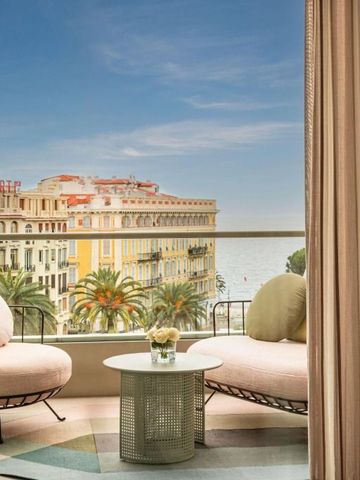 Balkon mit Sitzgelegenheiten und Meerblick, umgeben von eleganten Gebäuden.