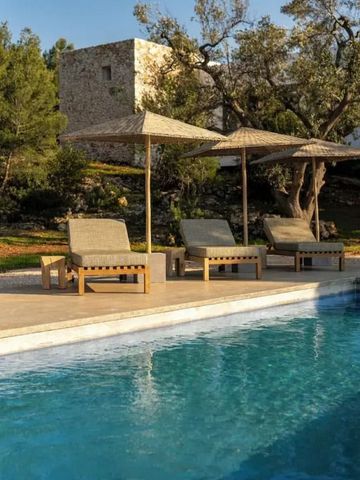 Liegestühle und Sonnenschirme am Pool mit Steinmauern und Bäumen