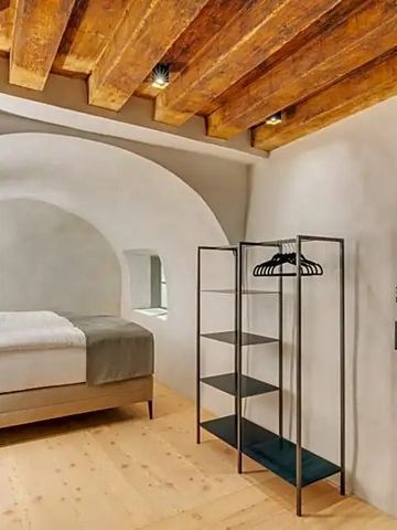 Elegantes Zimmer mit Holzbalkendecke und modernem Bett.