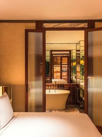 Luxuriöses Zimmer mit freistehender Badewanne und eleganten Holztüren.