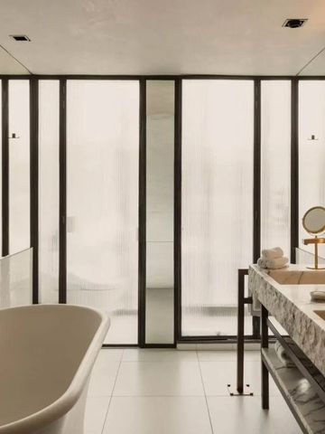 Badezimmer mit freistehender Badewanne und großen Fenstern.