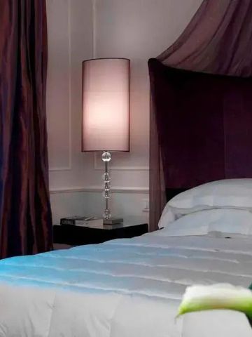 Elegantes Schlafzimmer mit Nachttischlampe und lila Vorhängen