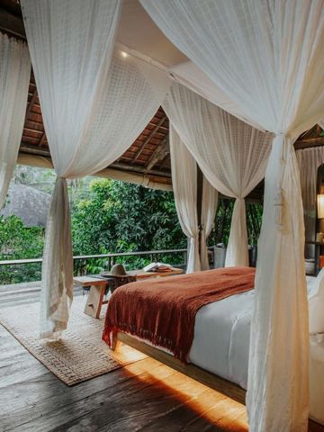 Luxuriöses Schlafzimmer mit weißen Vorhängen und grüner Aussicht im Buahan a Banyan Tree Escape