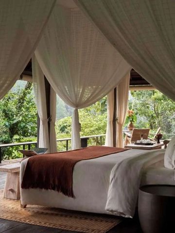 Himmelbett in offener Villa mit Blick auf üppige Vegetation.