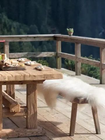 Holztisch auf Terrasse mit Blick auf bewaldete Berge