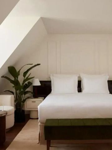 Elegantes Schlafzimmer mit Dachschräge, schickem Bett und moderner Einrichtung